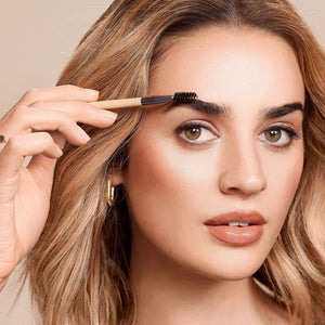 Woman applying product with a brow spoolie brush held near her eyebrow