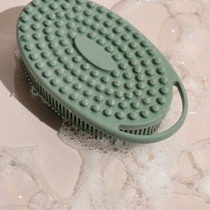 Sage green silicone body scrubber submerged with raised circular cleaning nodes