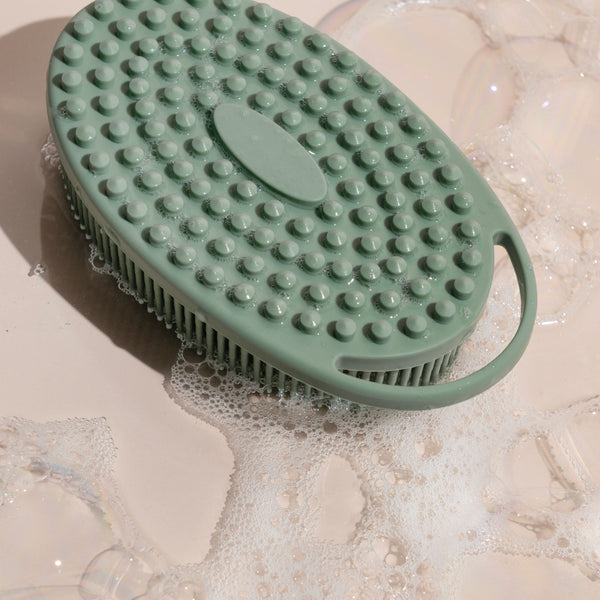 Sage green silicone body scrubber submerged with raised circular cleaning nodes