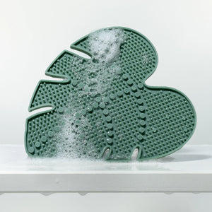Green leaf-shaped silicone makeup brush cleansing pad with foam and raised nubs
