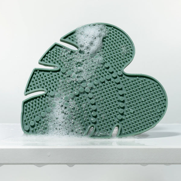 Green leaf-shaped silicone makeup brush cleansing pad with foam and raised nubs