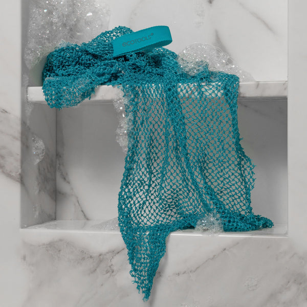 Teal bath exfoliating net with teal tag in water with visible bubbles