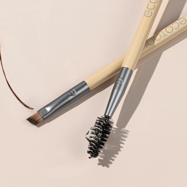 Eyebrow duo brush with angled bristle end and spoolie brush end on beige handle