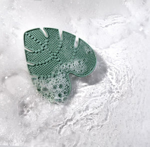 Green silicone makeup brush cleansing pad, leaf-shaped with raised cleaning nubs
