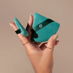 Two teal triangular powder puffs with dark green bands held in hands