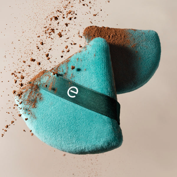 Teal triangular powder puff with dark green band and visible powder residue