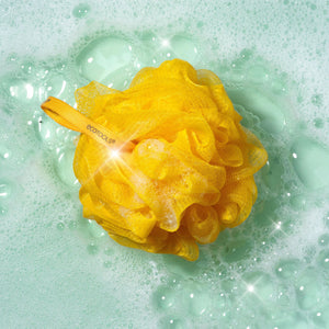 Yellow delicate EcoPouf bath sponge floating in water with bubbles