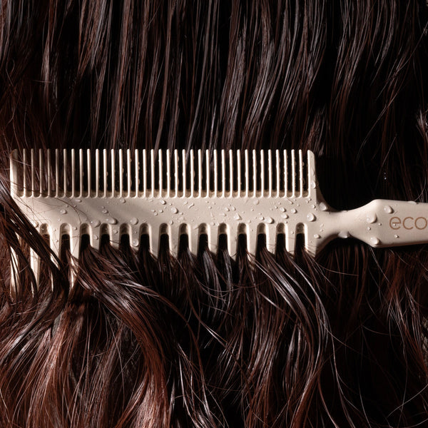 Double-sided comb brushing dark hair with narrow, evenly spaced teeth
