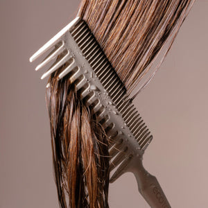 Close-up of double-sided hair comb lifting dark and brown hair strands