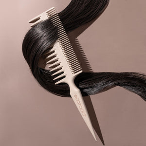 Double-sided comb with fine teeth and pointed tip grooming black hair strands