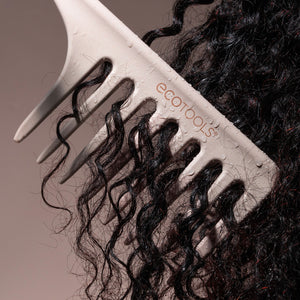 Wide tooth comb brushing through black curly hair, showing wide-spaced teeth