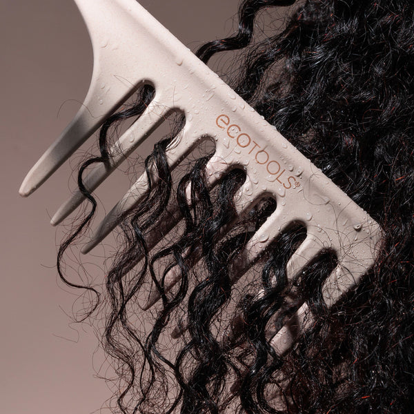 Wide tooth comb brushing through black curly hair, showing wide-spaced teeth