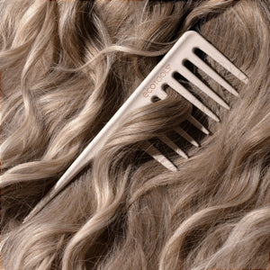 Wide tooth comb close-up gliding through blonde hair with wide teeth