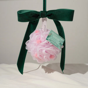 Pink mesh bath pouf gift with dark green satin bow tied to box