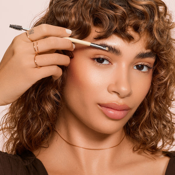 Eyebrow brush duo being used, angled bristle tip brushing eyebrow hairs