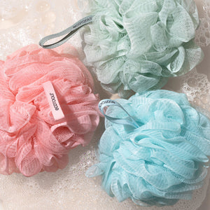 Assorted mesh cleansing poufs in pink, mint, and light blue with fabric tags