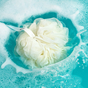 Cream mesh EcoPouf in foamy bath water, curled texture visible