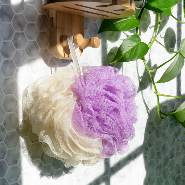 2-in-1 bath pouf hanging from a wooden hook, purple and cream